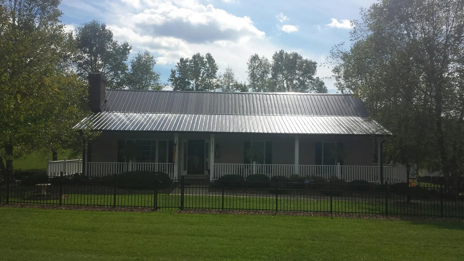 Gray metal roof on a brick ranch with a full width front porch — Gutter Guard Installation work by our crew in Hudson